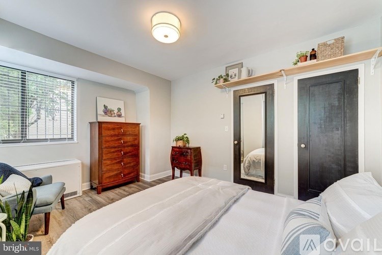 A bedroom with a bed, dresser, and window.
