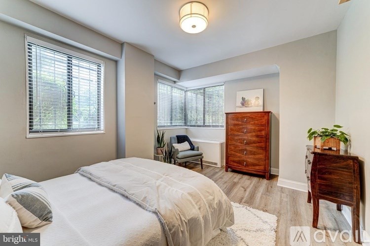 A bedroom with a bed, a dresser, and a window with blinds.