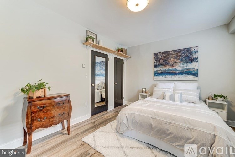 A bedroom with a bed, nightstand, and a painting on the wall.