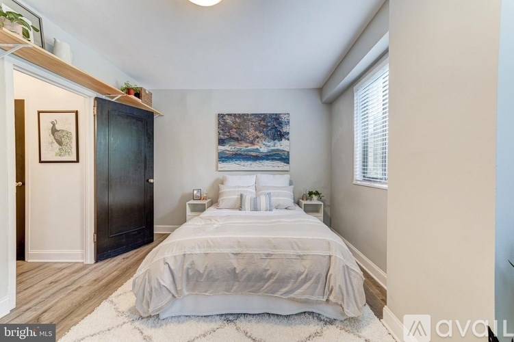 A bedroom with a large bed and a painting on the wall.