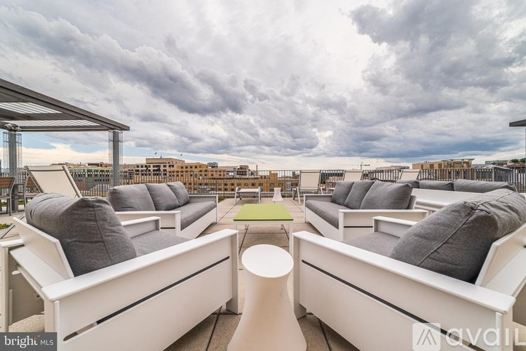 A bright outdoor seating area with white couches and a green mat.