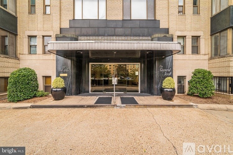 The front of a building with a black awning and two large planters.
