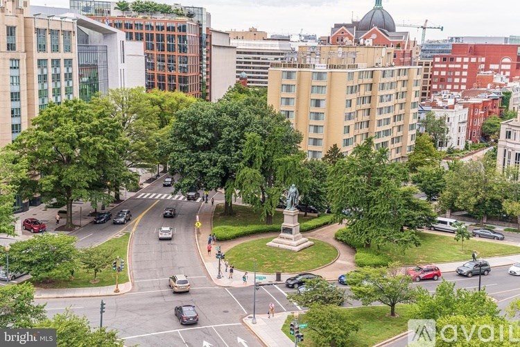 A city street with cars and a monument in the middle.