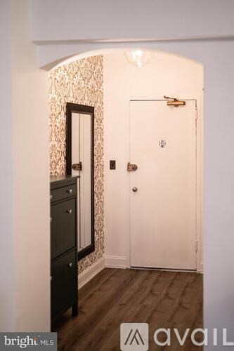 A hallway with a black dresser and a white door.