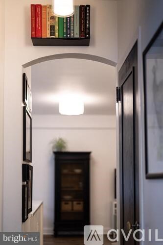 A hallway with a light on and a shelf with books on it.
