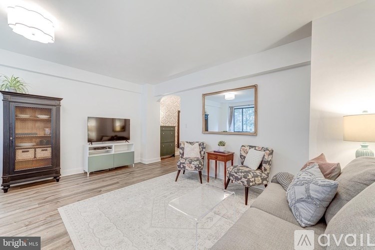 A living room with a grey sofa, a wooden table, and a mirror on the wall.