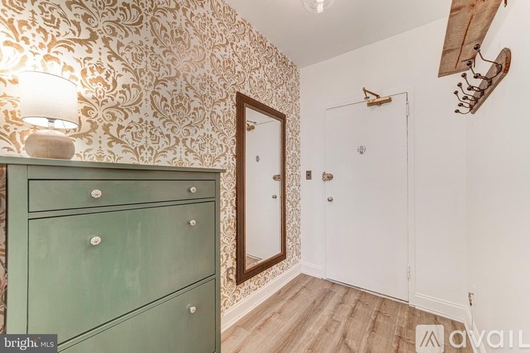 A room with a green dresser and a wallpapered wall.