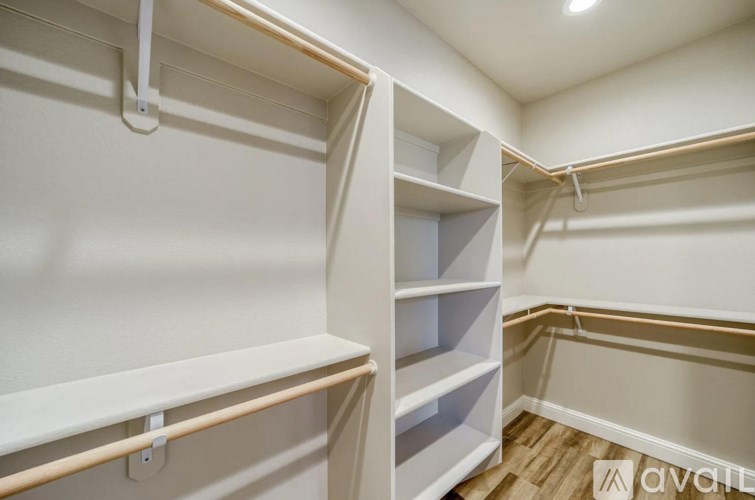 A white walk-in closet with shelves and a wooden floor.