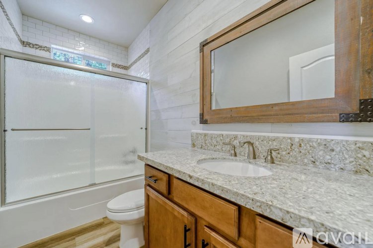A bathroom with a marble countertop and a wooden framed mirror.