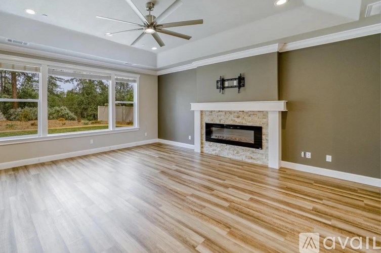 A spacious living room with a fireplace and a ceiling fan.