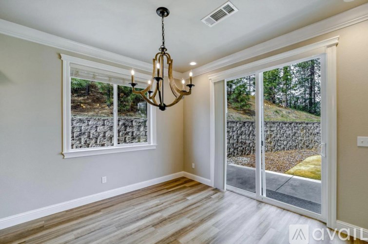 A room with a chandelier and sliding glass doors.