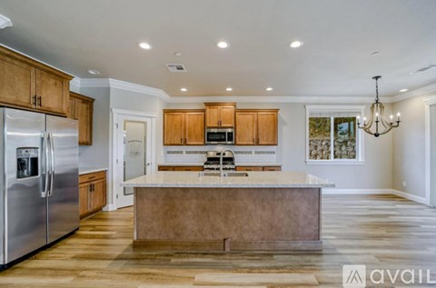 A kitchen with wooden cabinets and a marble island.