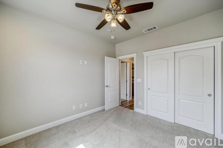 A room with a ceiling fan and white walls.