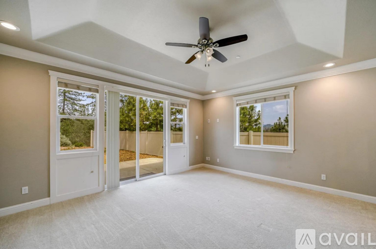 A spacious room with a ceiling fan and sliding glass doors.