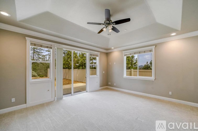 A spacious room with a ceiling fan and sliding glass doors.