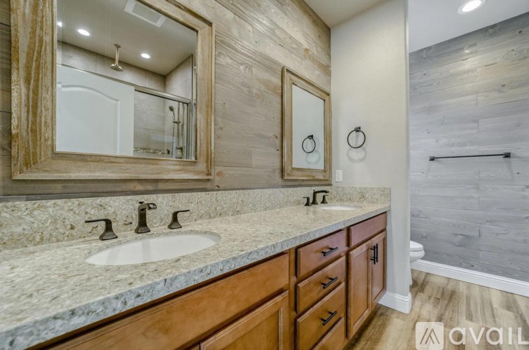 A bathroom with a marble countertop and wooden cabinets.