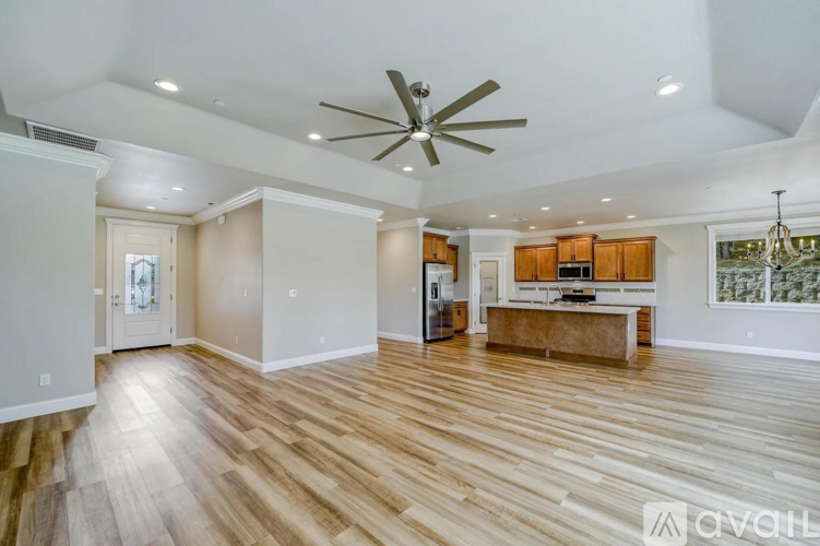 A spacious living room with wooden flooring and a ceiling fan.
