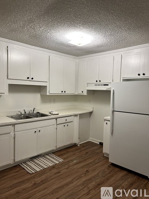 A kitchen with white cabinets and a white refrigerator.
