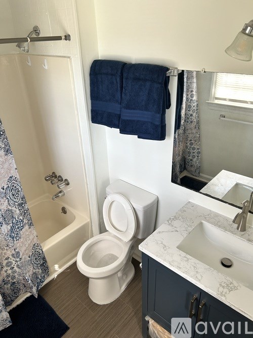 A white toilet is in a bathroom with a blue towel hanging on the wall.