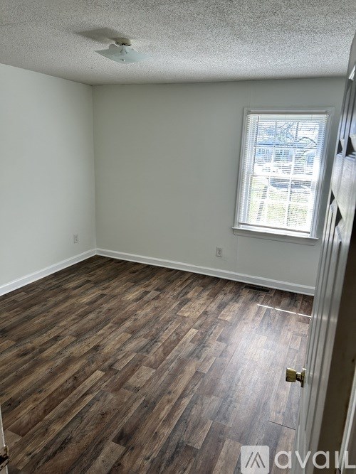 A room with wooden flooring and a window with blinds.