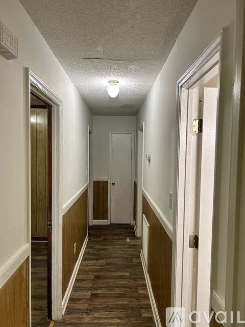 A long hallway with wood floors and white walls.