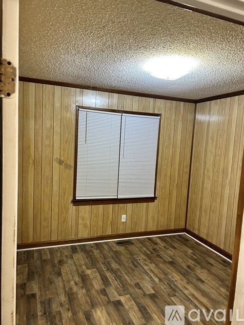 A room with wooden walls and a window with blinds.