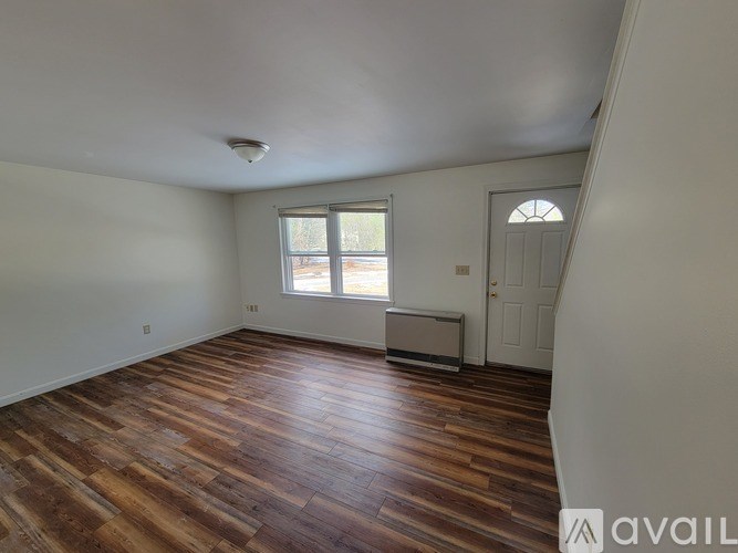 A room with wooden flooring and a window.