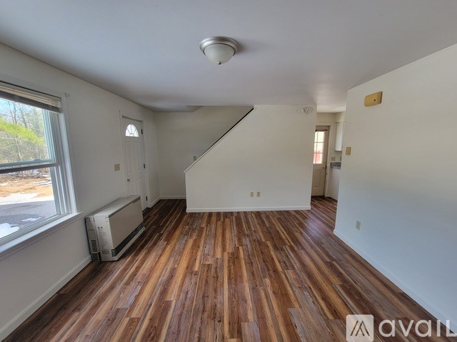 A room with wooden floors and white walls is available for rent.