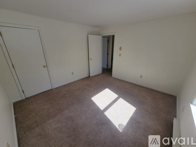 A carpeted room with a door and a window.