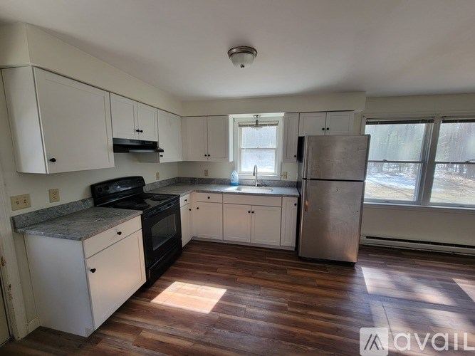 A kitchen with white cabinets and a stainless steel refrigerator.