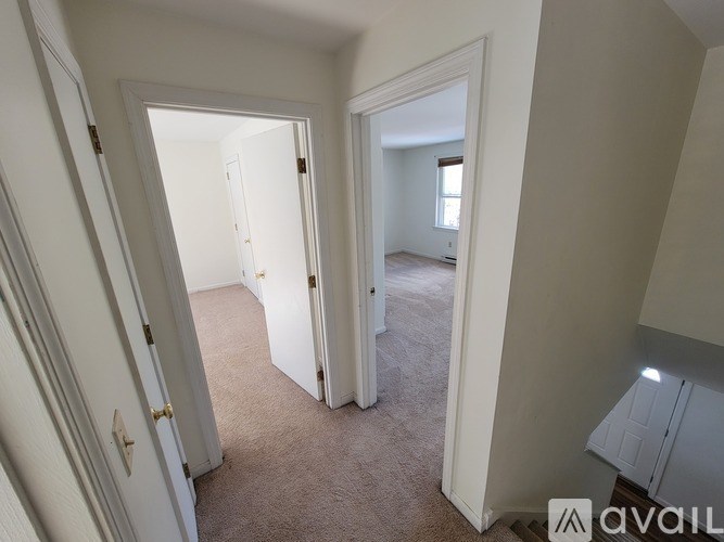 A hallway with a carpeted floor and white walls.