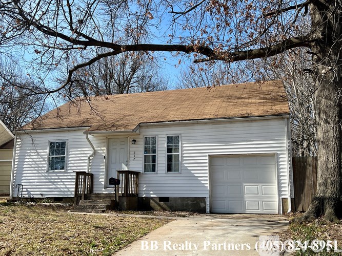 A white house with a brown roof and a garage door.