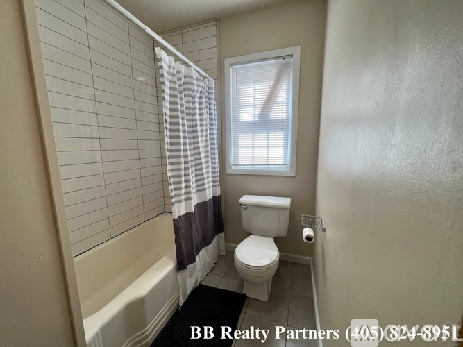 A bathroom with a toilet, tub, and window.