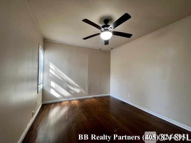 A room with a ceiling fan and wooden flooring.