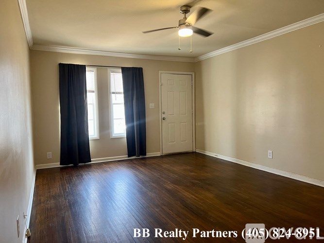 A room with a ceiling fan and wooden flooring.