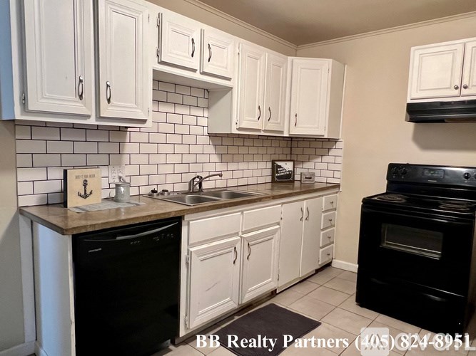 A kitchen with white cabinets and black appliances.