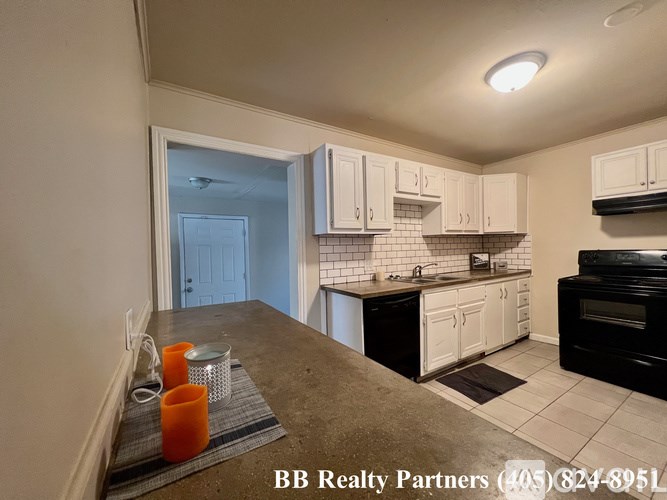 A kitchen with black appliances and white cabinets.