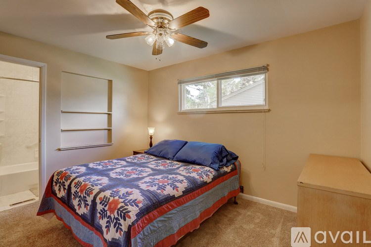 A bedroom with a bed, a ceiling fan, and a window.