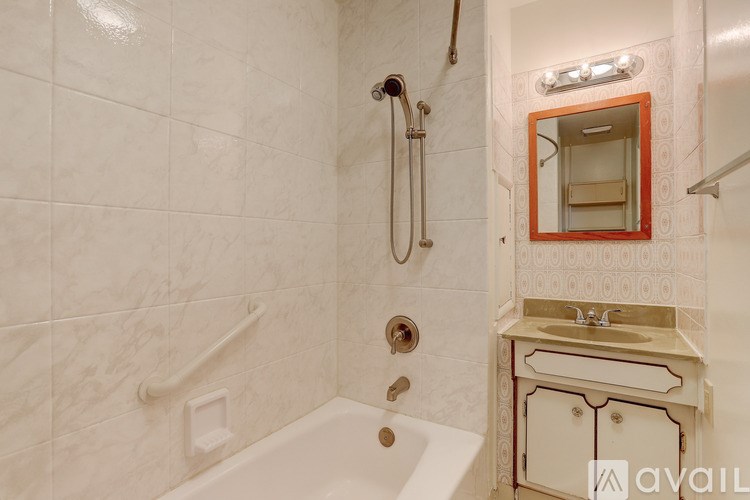 A bathroom with a white tub and a sink with a red mirror.
