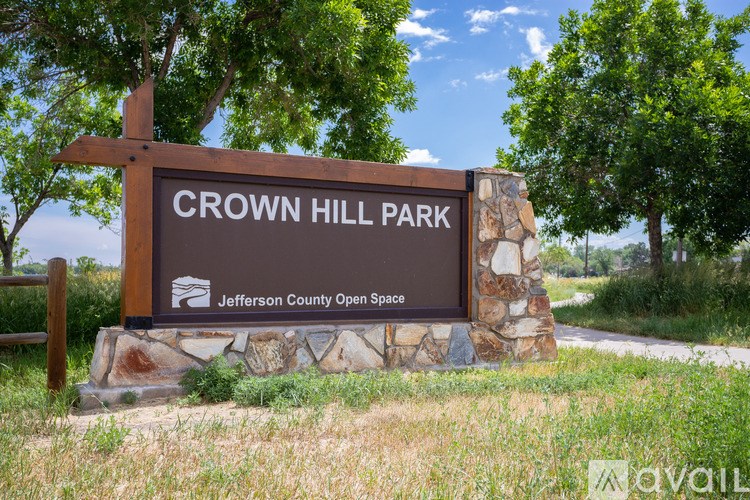 A sign for Crown Hill Park stands in front of a grassy area.