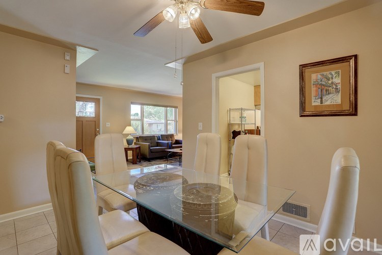 A dining room with a glass table and white chairs.