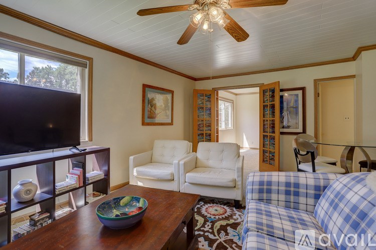 A living room with a ceiling fan and a flat screen TV.