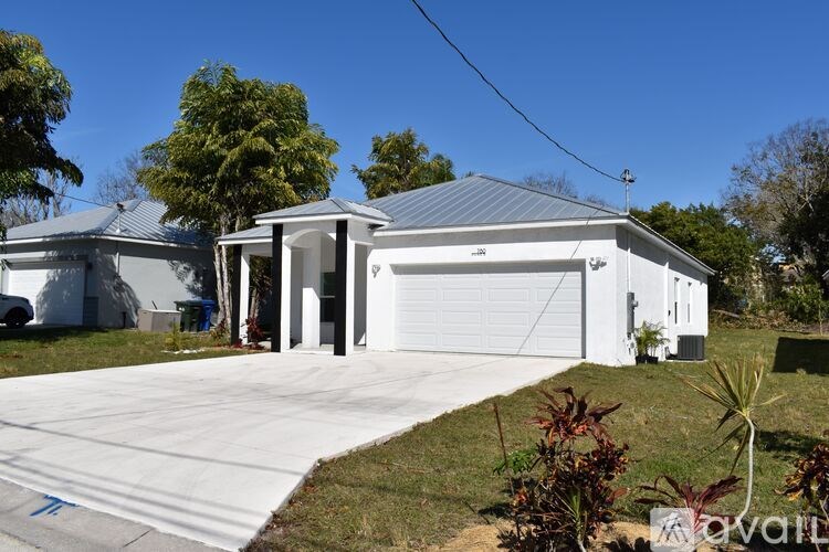 A house with a white garage door is surrounded by greenery.