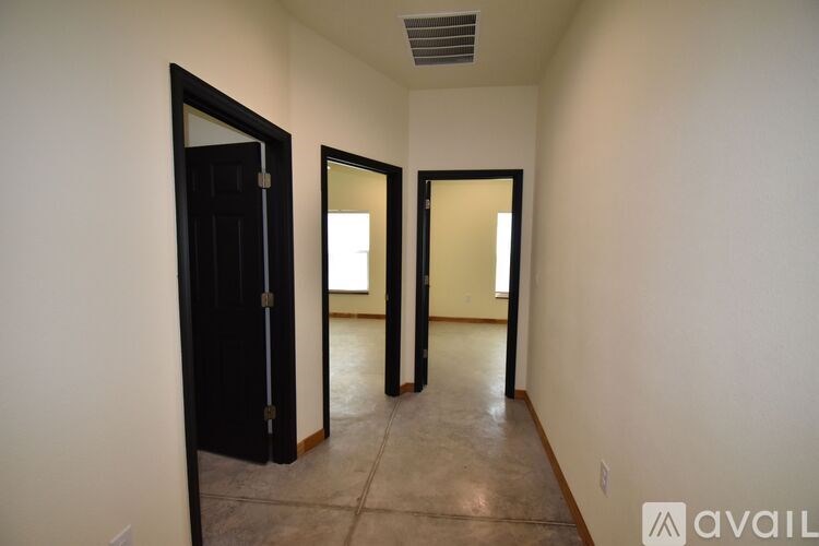 A hallway with three doors and a mirror on the wall.
