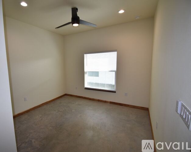 A room with a ceiling fan and a window with blinds.