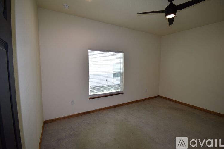 A room with a ceiling fan and a window with blinds.