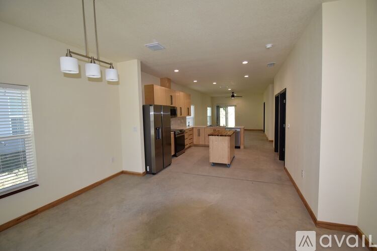 A spacious, empty room with a kitchen area in the background.