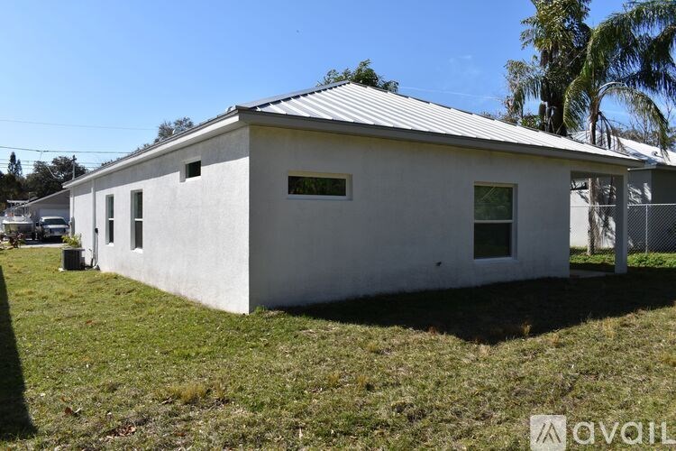 A small white building with a metal roof and a fence in front.