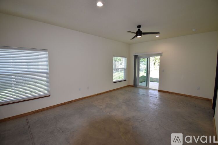 A room with a ceiling fan and a window with blinds.