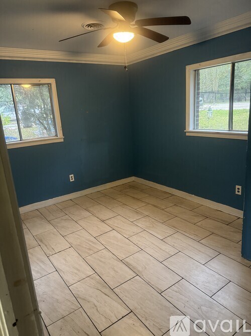 A room with a ceiling fan and two windows.